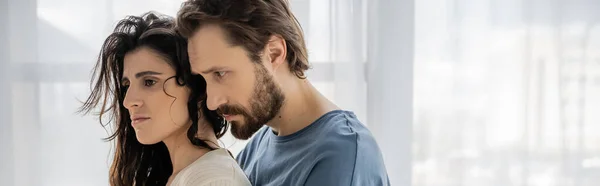 Бородатый мужчина смотрит на расстроенную девушку брюнетку дома, баннер — стоковое фото