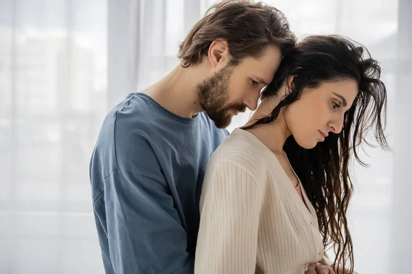 Side view of sad bearded man hugging girlfriend at home — Stock Photo