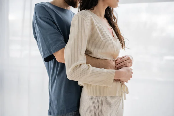 Ausgeschnittene Ansicht von Mann im Pyjama umarmt brünette Freundin zu Hause — Stockfoto