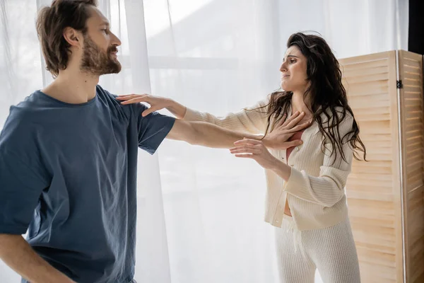 Abusive man pushing scared girlfriend in pajama at home — Stock Photo