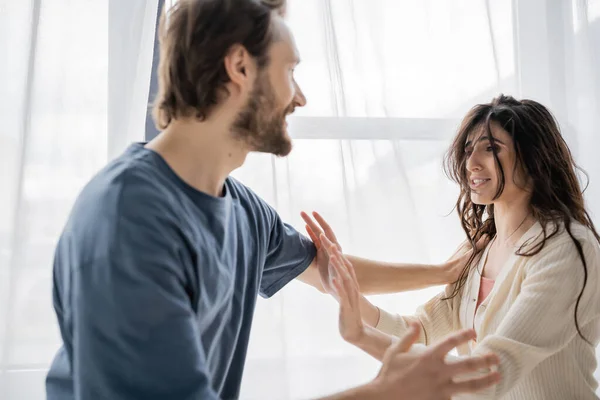 Frightened woman showing stop gesture at angry boyfriend during conflict at home — Stock Photo
