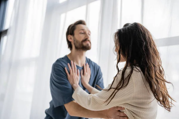 Woman pushing blurred aggressive boyfriend during quarrel at home — Stock Photo