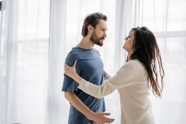 Aggressive man looking at frightened girlfriend during relationship crisis at home — Stock Photo