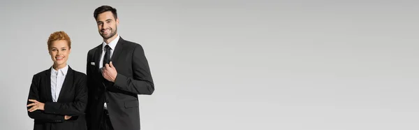 Erfolgreiche Geschäftskollegen in schwarzen schicken Blazern lächeln vereinzelt in die Kamera auf grauem Banner — Stockfoto