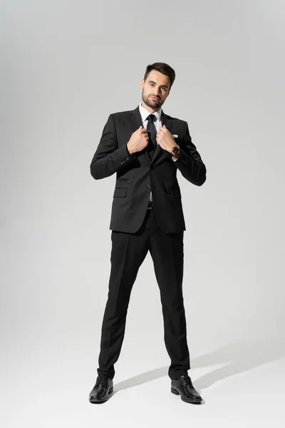 Comprimento total no empresário confiante em preto elegante pantsuit no fundo cinza — Fotografia de Stock