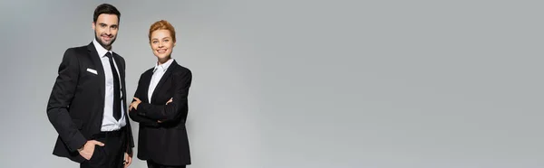 Радісні бізнес-колеги в стильному формальному одязі посміхаються на камеру ізольовані на сірому, банер — стокове фото