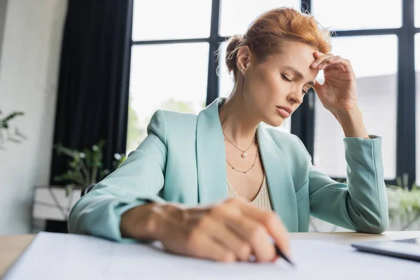 Виснажена бізнес-леді з закритими очима страждає від головного болю, сидячи на робочому місці в офісі — стокове фото