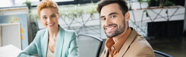 Erfolgreiche Geschäftspartner in stylischen Blazern, die im Büro in die Kamera lächeln, Banner — Stockfoto
