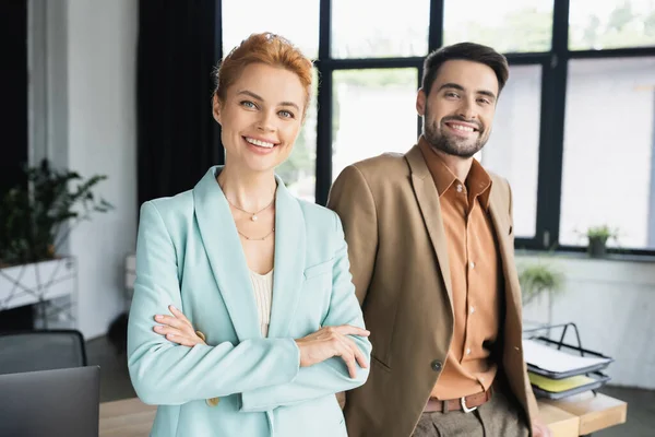 Fröhliche und erfolgreiche Geschäftspartner in trendigen Anzügen blicken im Büro in die Kamera — Stockfoto