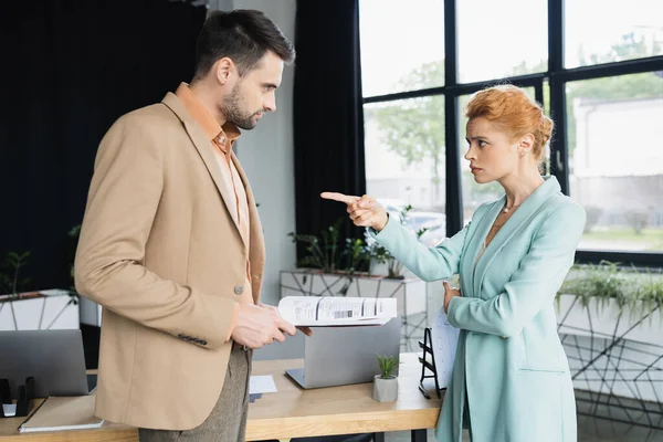 Angry businesswoman quarreling and pointing at manager with documents in office — Stock Photo
