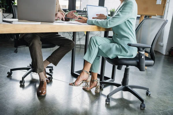 Обрезанный вид стильных бизнес-коллег, указывающих руками на ноутбуки в офисе — стоковое фото