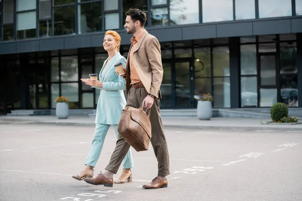 Erfolgreiche Manager in modischen Anzügen, die mit Coffee to go auf die Straße gehen — Stockfoto