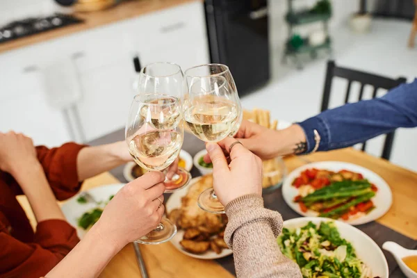Partial view of gay man clinking wine glasses with parents and boyfriend near delicious supper in kitchen — Stock Photo