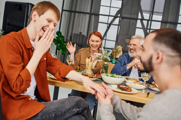 Blurred gay may making marriage proposal to amazed boyfriend during family supper in living room — Stock Photo