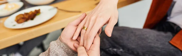 Cropped view of gay man holding hand of boyfriend with wedding ring while making marriage proposal in kitchen, banner — Stock Photo