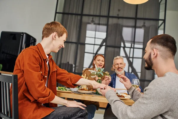 Gay man holding wedding ring while making marriage proposal to boyfriend during family supper at home — Stock Photo