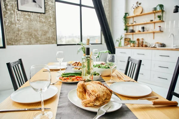 Стол подается с жареной курицей и овощами возле бутылки вина на современной кухне — стоковое фото