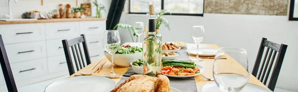 Bottiglie e bicchieri di vino vicino al pollo fritto e verdure servite sul tavolo in cucina moderna, banner — Foto stock