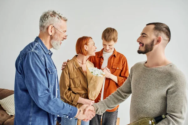 Bearded man shaking hands with gay partner of son at home — Stock Photo