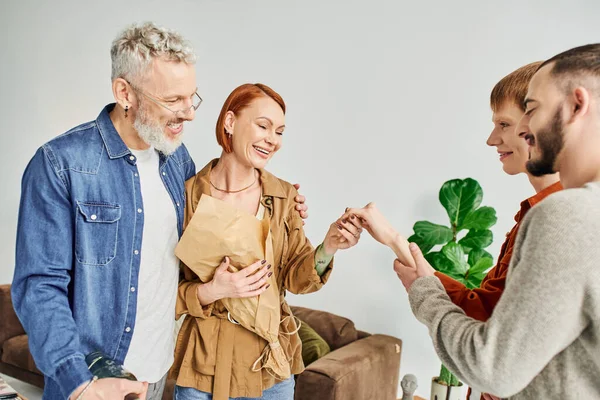 Engaged gay man showing hand to happy parents near boyfriend at home — Stock Photo