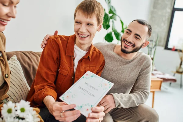 Overjoyed gay man showing wedding invitation to smiling mother at home — Stock Photo