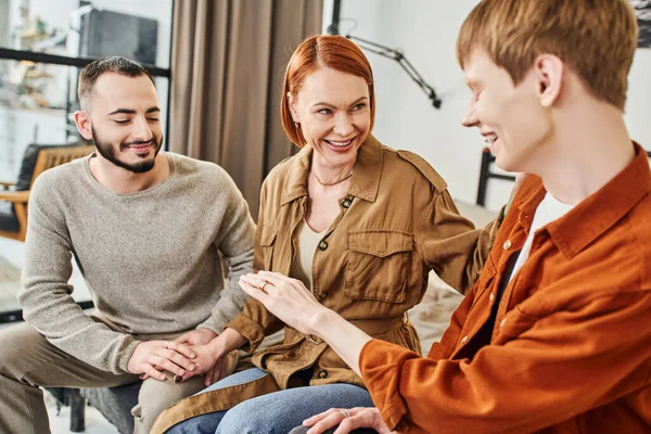 Blurred gay man showing wedding ring to overjoyed mother near boyfriend at home — Stock Photo