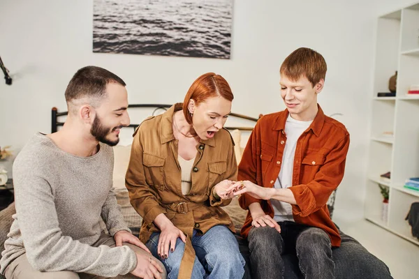 Smiling gay man showing wedding ring to amazed mother in bedroom — Stock Photo