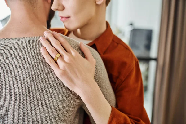 Vista parcial de hombre gay en anillo de boda abrazando pareja en casa - foto de stock