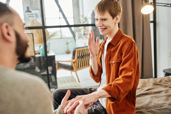 Blurred gay man making marriage proposal to redhead boyfriend in braces at home — Stock Photo