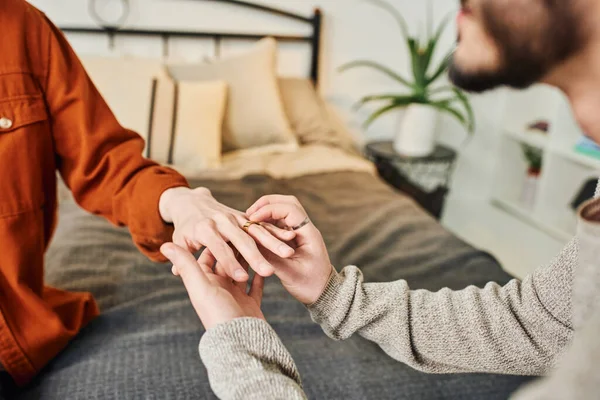 Cropped view of gay man wearing wedding ring on boyfriend while making marriage proposal in bedroom — Stock Photo
