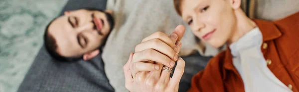 Top view de jovem casal gay de mãos dadas enquanto deitado na cama em casa, banner — Fotografia de Stock
