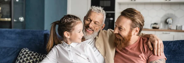Carefree preteen girl looking at gay parents at home, banner — Stock Photo