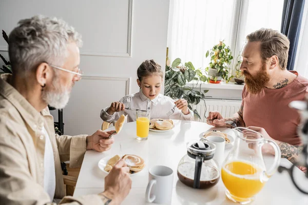 Tätowierte gleichgeschlechtliche Eltern frühstücken mit Tochter zu Hause — Stockfoto