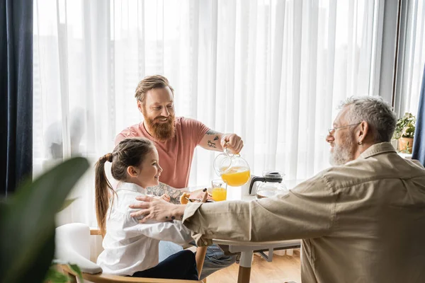 Positive same sex parents having breakfast with preteen daughter at home — Stock Photo