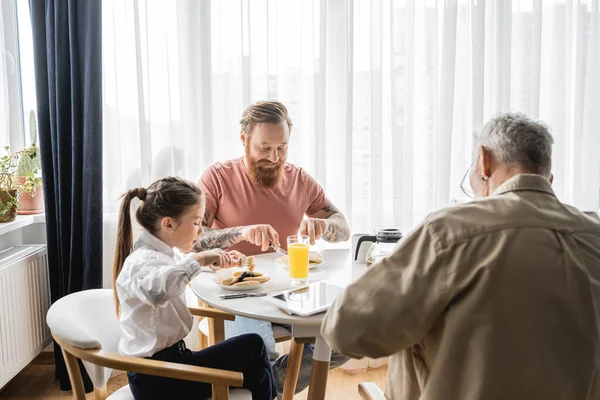 Adopté fille prendre le petit déjeuner avec gay parents à la maison — Photo de stock