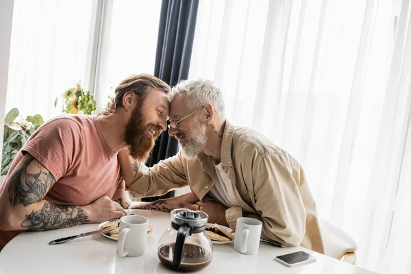 Allegro gay uomo abbracciare partner vicino colazione e caffè a casa — Foto stock