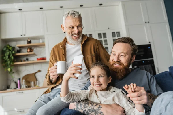 Smiling preteen girl taking selfie with bearded homosexual parents at home — Stock Photo