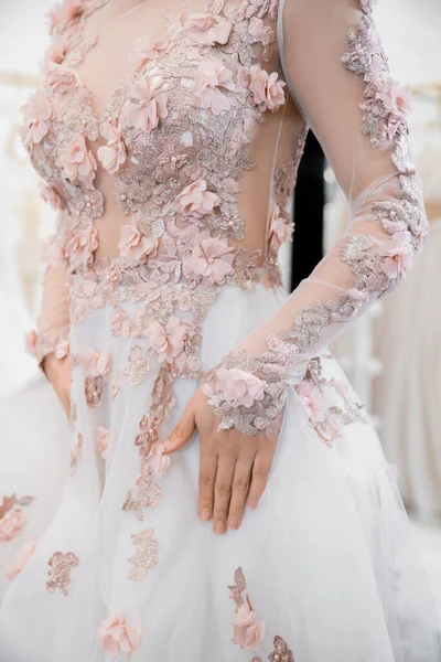 Ausgeschnittene Ansicht einer Frau, die in einem wunderschönen und floralen Hochzeitskleid in einem luxuriösen Salon um verschwommene weiße Tüll-Stoffe steht, Brauteinkäufe, zukünftige Braut, Details, Vorbereitung für einen besonderen Tag — Stockfoto
