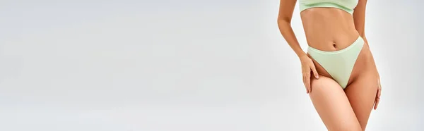 Ausgeschnittene Ansicht des sexy Models in hellgrünem BH und Höschen, die im Stehen die Hüfte berühren und isoliert auf grau posieren, Selbstakzeptanz und körperpositives Konzept, Banner mit Kopierraum — Stockfoto