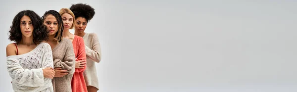Donne multietniche fiduciose in maglioni lavorati a maglia che incrociano le braccia e posano isolate su tipi di corpo grigi, diversi e accettazione di sé, rappresentazione multiculturale, banner con spazio su copia — Foto stock