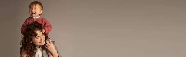 Maternità amorevole, genitorialità e carriera, donna d'affari e bambino felice su sfondo grigio, bambino sulle spalle, concetto di armonia della vita lavorativa, maternità amorevole, tempo di qualità, banner — Foto stock