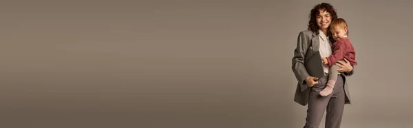 Armonia della vita lavorativa, felice madre che tiene il computer portatile e la figlia del bambino su sfondo grigio, gestione del tempo, fiducia in se stessi, genitorialità moderna, successo professionale, donna d'affari, banner — Foto stock