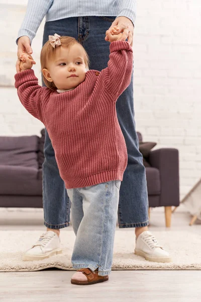 First steps, quality family time, bonding, balancing work and life, working mother holding hands with toddler daughter, togetherness, cozy living room, denim jeans, casual attire — Stock Photo