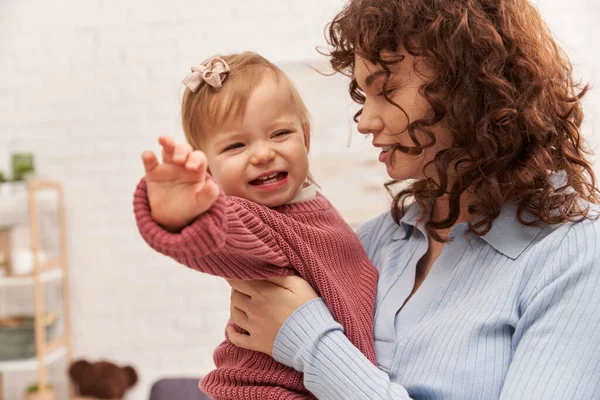 Balanced lifestyle, working mother with curly hair holding in arms baby girl, woman and her toddler daughter, modern parenting, work life harmony, engaging with kid, crying baby girl — Stock Photo