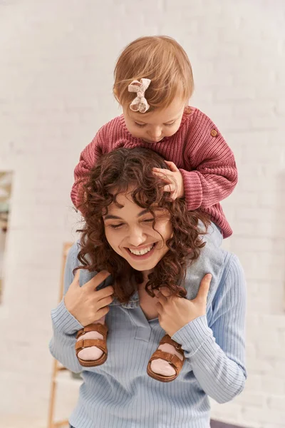 Mujer sonriente con niña sobre los hombros, estilo de vida equilibrado, tiempo de mamá hija, divertirse juntos, tiempo de calidad, trabajo y armonía de la vida, maternidad amorosa, felicidad - foto de stock