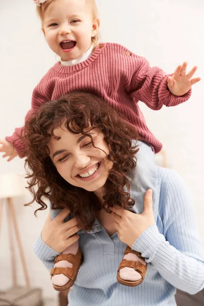 Mujer alegre con la muchacha feliz del bebé en hombros, estilo de vida equilibrado, tiempo de la hija de la mamá, divertirse juntos, tiempo de calidad, trabajo y armonía de la vida, maternidad cariñosa, felicidad — Stock Photo