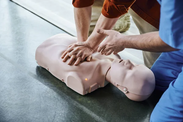 Семинар по оказанию первой помощи, частичное представление о враче-инструкторе, указывающем рукой и помогающем человеку делать массаж грудной клетки на маникене, концепция спасательных навыков и техник — стоковое фото