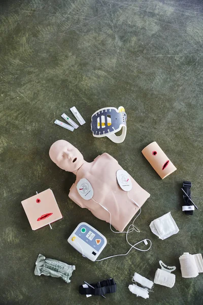 Top view of CPR manikin, automated defibrillator, wound care simulators, compression tourniquets, neck brace and bandages, medical equipment for first aid training and skills development — Stock Photo