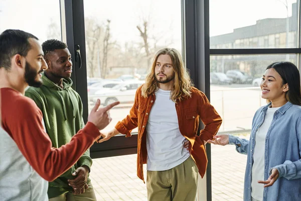 Ambitious and stylish multiethnic colleagues gesturing and discussing startup project in modern office space, creative thinking, young and diverse business people collaboration — Stock Photo