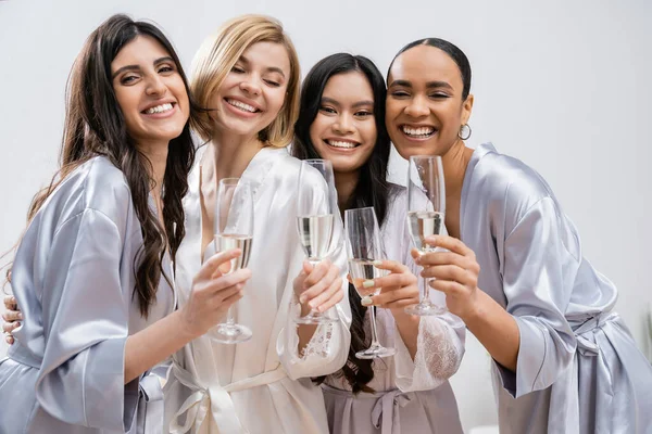 Chuveiro nupcial, namoradas multiculturais segurando óculos com champanhe, celebração antes do casamento, mulheres morenas e loiras, noiva e suas damas de honra, diversas etnias, positividade — Fotografia de Stock